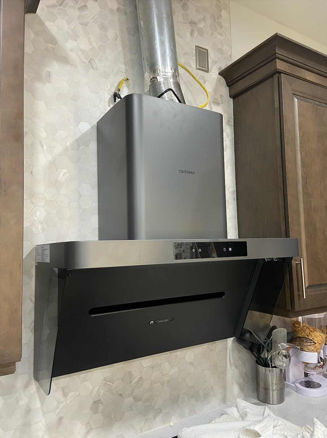 Wall-mounted range hood showing rigid galvanized steel ductwork with straight vertical connection above gas range in white subway tile kitchen