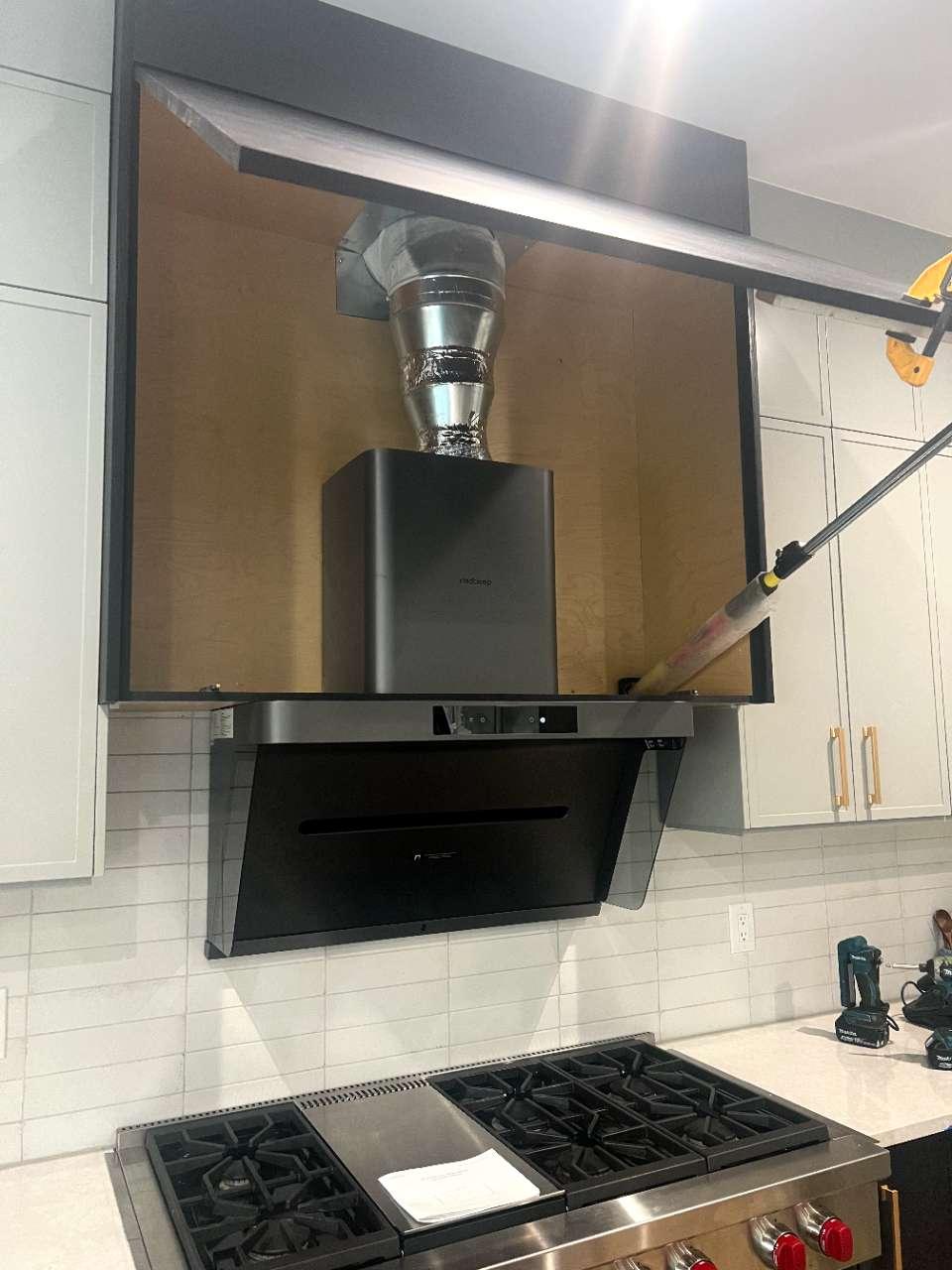 Incorrect flexible corrugated aluminum foil duct connected to range hood outlet inside cabinet showing improper installation method