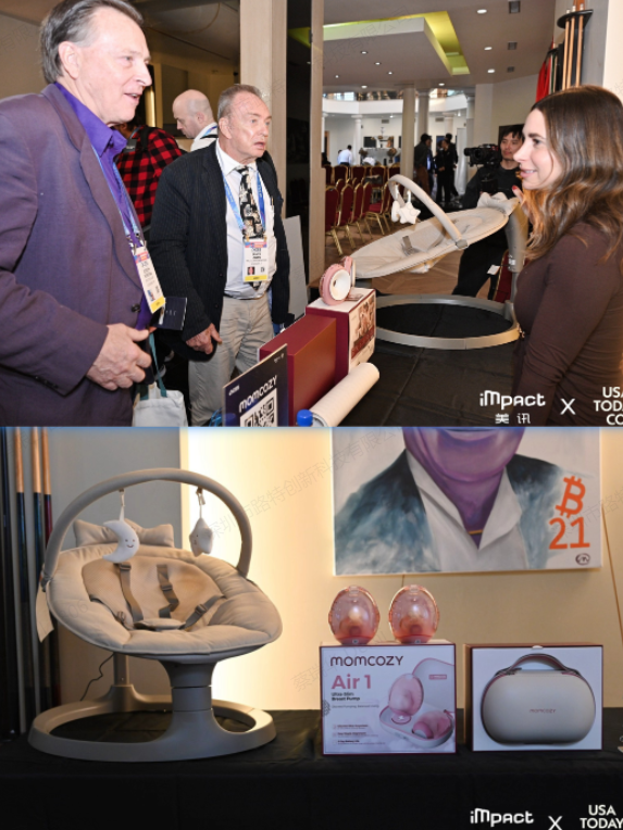 Two men in suits conversing while standing in front of a display table showcasing the Momcozy baby swing and Air 1 breast pump at a trade show