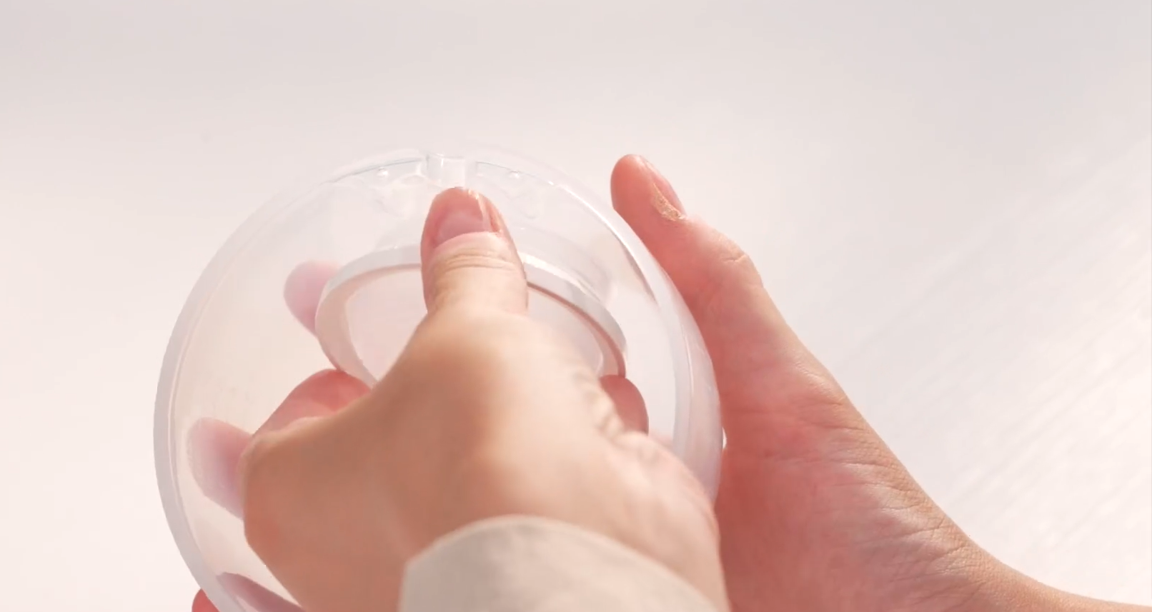 Hands assemble clear silicone breast pump flange
