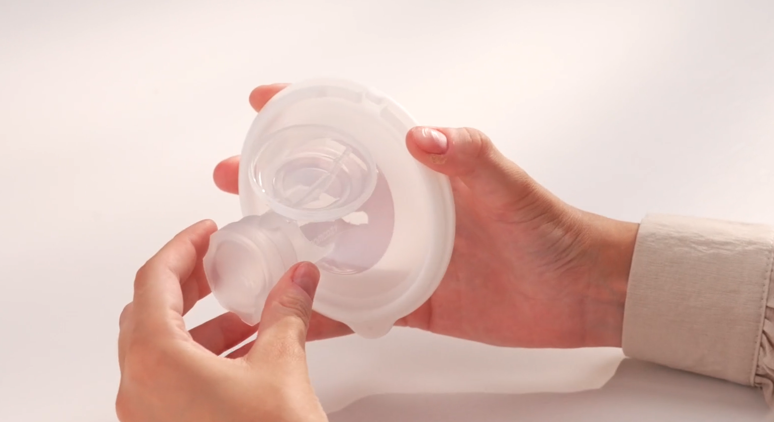 Hands assembling clear silicone breast pump flange