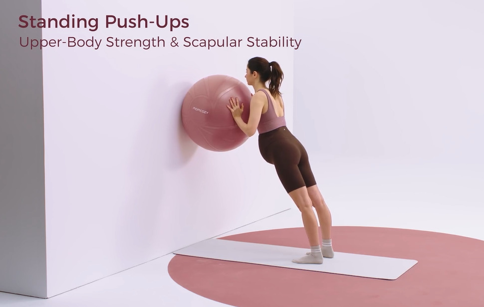 Woman doing standing stability ball push-ups for upper body strength